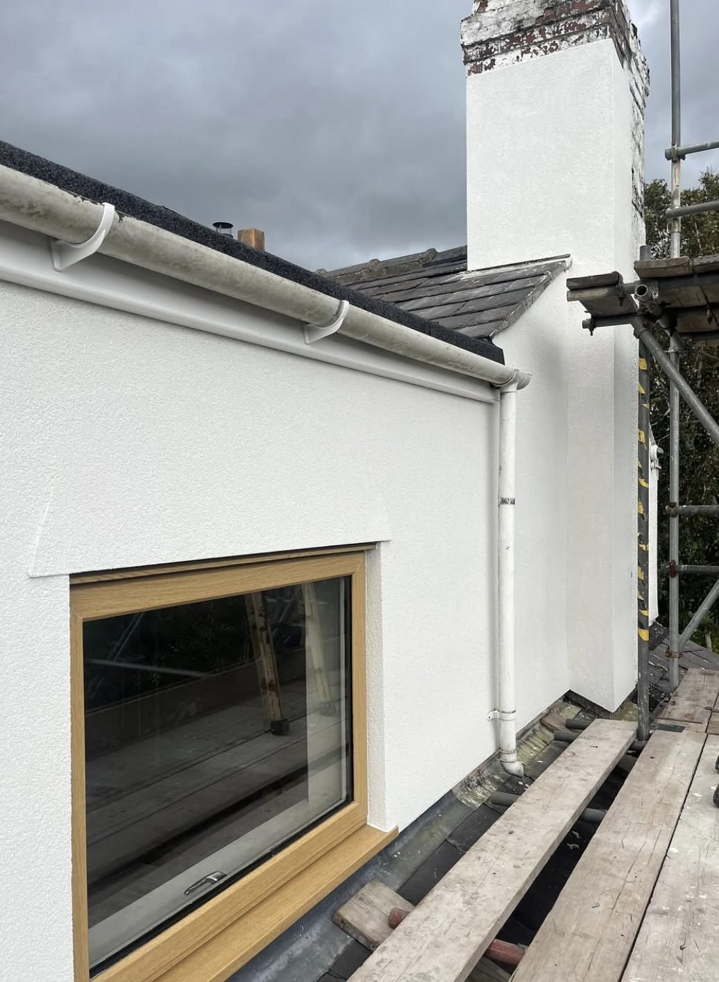Chimney stack and dormer cheek in a new white finish, seen from scaffold
