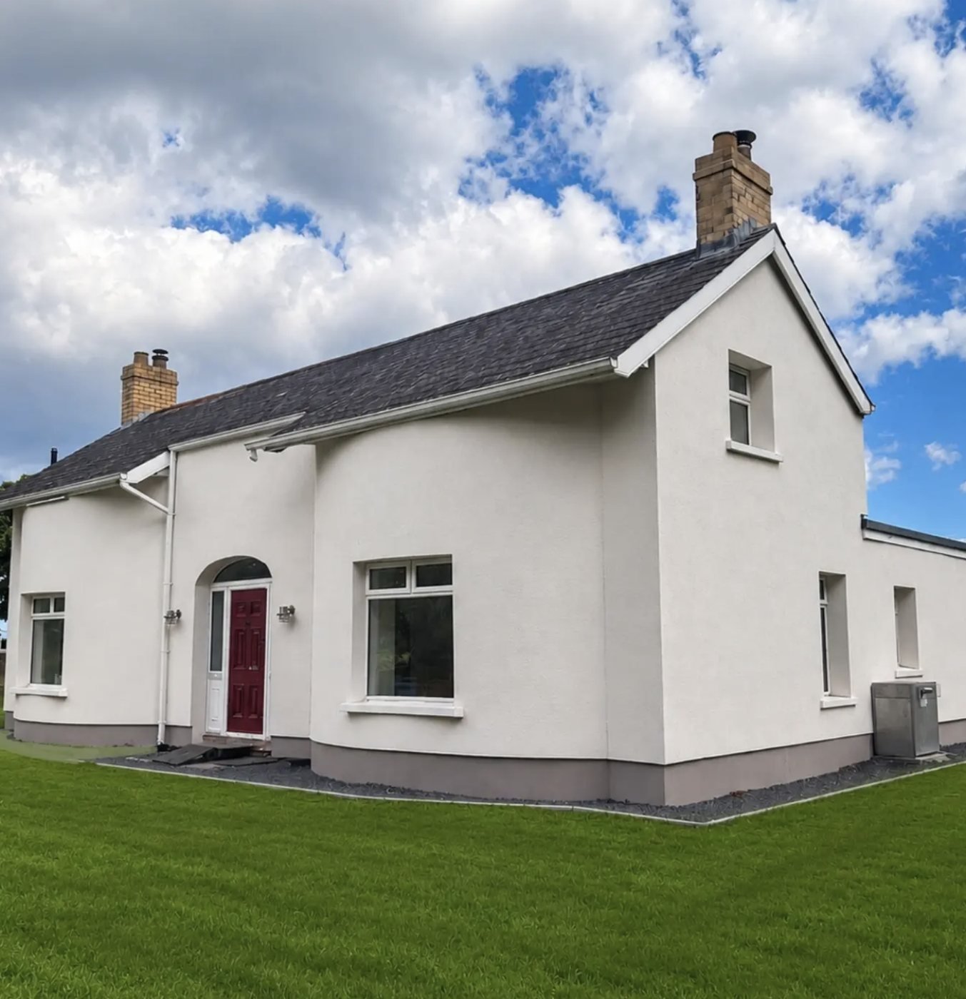 Detached cottage with curved walls in white and a grey plinth