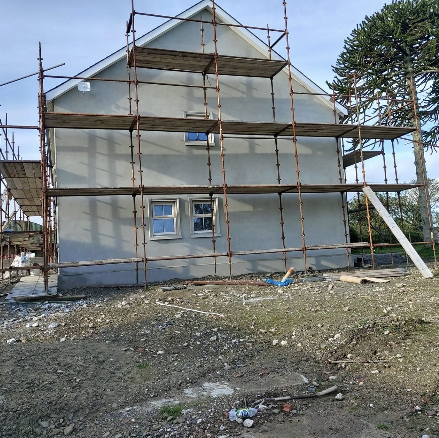 Gable wall in grey basecoat with three lifts of scaffolding