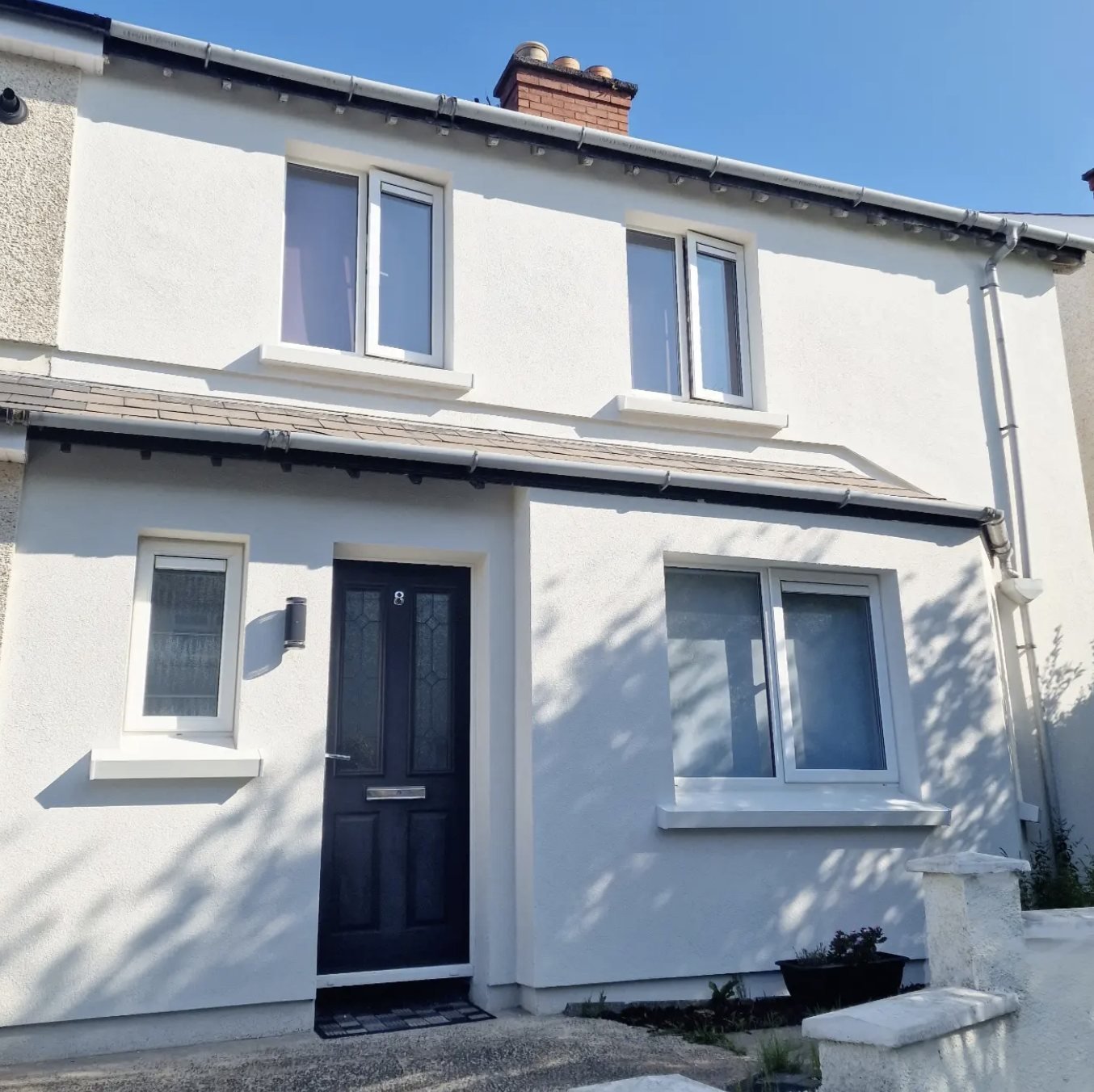 Terraced house in white with deep projecting sills and a black door
