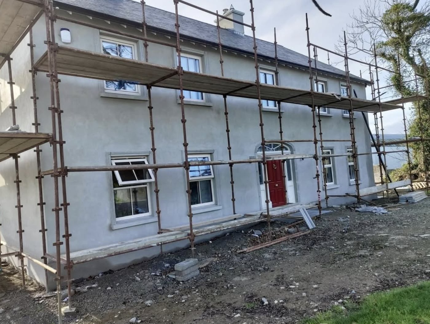 Long two-storey front in grey basecoat with scaffolding up